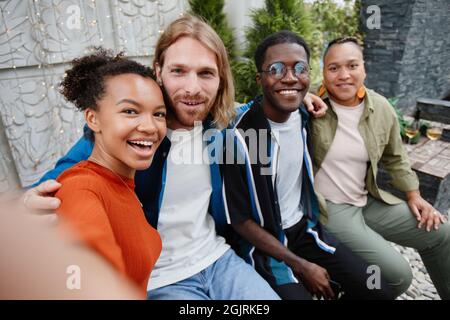 POV diverse group of young people looking at camera via video chat while having fun during outdoor party at rooftop Stock Photo
