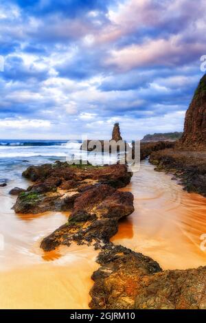 Cathedral rock and rugged terrain of basalt rock formations on Jones beach in Kiama bombo quarry site - seascape sunset. Stock Photo