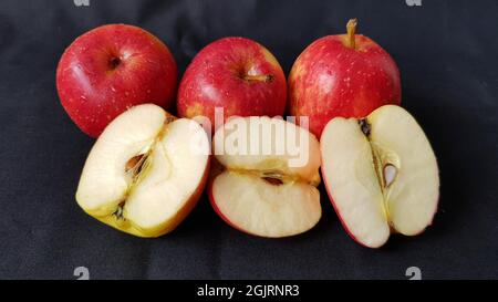 Malang, Indonesia - August 26, 2021 :  three red apples and half an apple on a black background Stock Photo