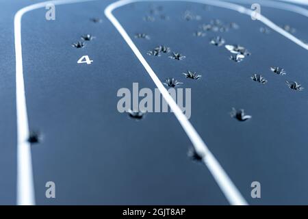 Close up shot with a shallow depth of field of a black paper silhouette target that has multiple bullet holes within in. Stock Photo