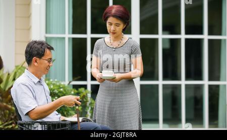 Senior male sitting and relax in backyard with wife Stock Photo