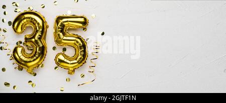 golden foil balloon number thirty five. Birthday or anniversary card with the inscription 35. gray concrete background. Anniversary celebration. Banne Stock Photo