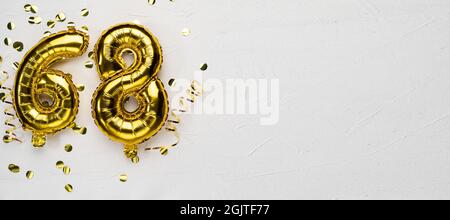 golden foil balloon number sixty eight. Birthday or anniversary card with the inscription 68. gray concrete background. Anniversary celebration. Banne Stock Photo