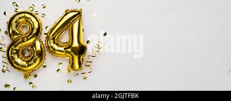 golden foil balloon number eighty four. Birthday or anniversary card with the inscription 84. gray concrete background. Anniversary celebration. Banne Stock Photo