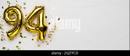 golden foil balloon number ninety four. Birthday or anniversary card with the inscription 94. gray concrete background. Anniversary celebration. Banne Stock Photo