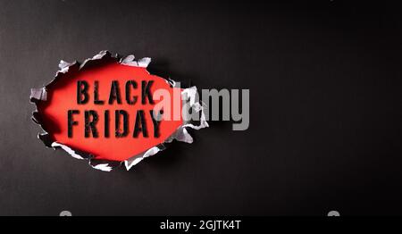 Top view of black torn paper and the text Black Friday on back and red background. Black Friday composition. Stock Photo