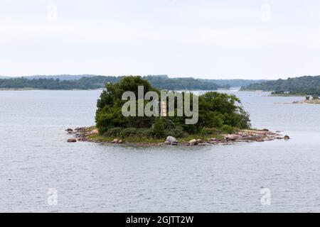 Navigation sign on a small island. Trees and solar panel on a pole. The archipelago. Stock Photo