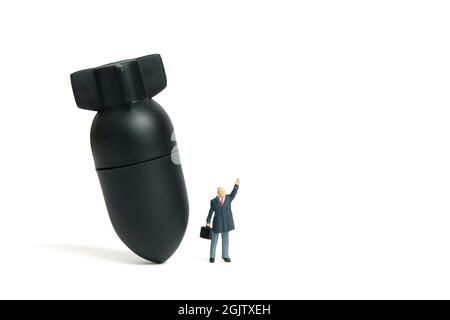 Miniature people toy figure photography. A businessman standing in front of bomb nuclear missile while raise his hand. Isolated on white background. I Stock Photo