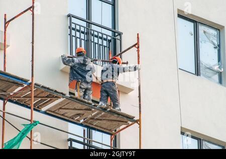 Two workers assembling scaffolding on city building Stock Photo
