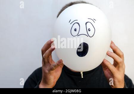 A man is holding a balloon with his face painted on it. The ball Stock Photo