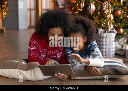 Happy biracial mom and daughter use tablet at home Stock Photo