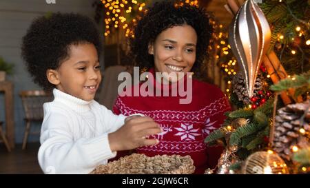 Smiling biracial mom and son decorate fir tree Stock Photo