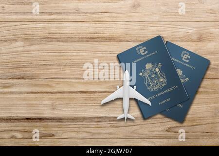 Plane model and antigua and barbuda passport  on wooden background, flat lay. Space for text Stock Photo