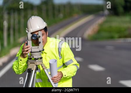 Close up of Asian surveyor engineer worker making measuring with theodolite on road works. survey engineer at road construction site, Surveyor equipme Stock Photo