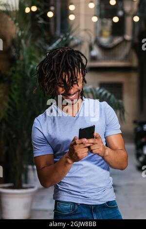 vertical portrait of a young latin man using his phone in the street at evening Stock Photo