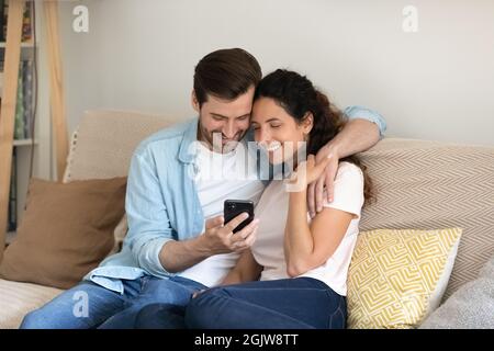 Couple resting on sofa using smartphone enjoy online shopping Stock Photo