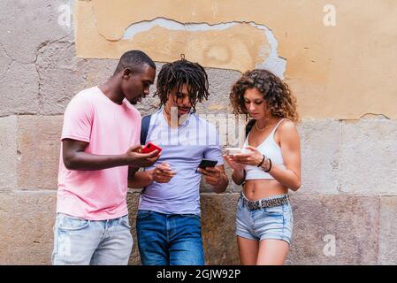 multi-ethnic group of young tourists standing up on the street checking their phones Stock Photo