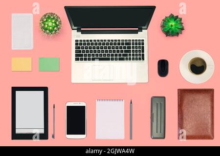 Modern workspace, technology working desk with laptop computer, coffee cup, office supplies, e-book and smartphone on pink pastel background with copy Stock Photo
