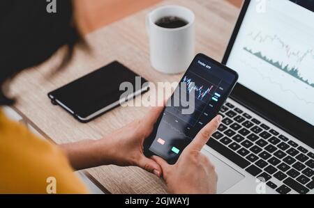 Trader business woman using trading stock market exchange app - Bitcoin, global economy concept - Focus on hands holding mobile phone Stock Photo