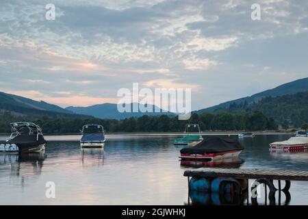 Motor boats moored on Loch Earn at Lochearnhead in rural Scotland. Captured at dusk. Stock Photo
