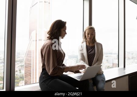 Women employees brainstorm discussing project on computer Stock Photo