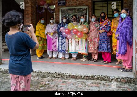 Non Exclusive: DHAKA, BANGLADESH - SEPTEMBER 11: A student of class three is seen taking photographs of some of the teachers and guardians of Kolotan Stock Photo