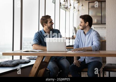 Smiling male colleagues joke working together on computer Stock Photo