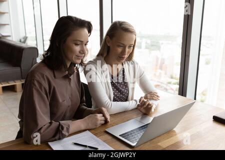 Female employees brainstorm on laptop at workplace Stock Photo