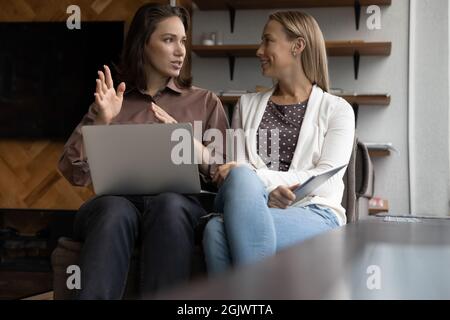 Female colleagues discuss business ideas using laptop Stock Photo