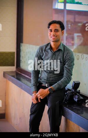 A vertical shot of a smiling handsome Indian male with a professional camera Stock Photo