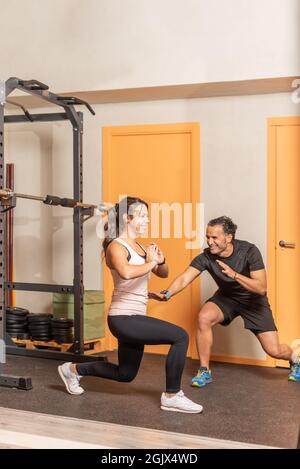 Young woman doing squats without weighting exercise in gym Stock Photo