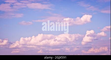 The sky with blurred cirrus and cumulus clouds illuminated by the setting sun. Natural background Stock Photo
