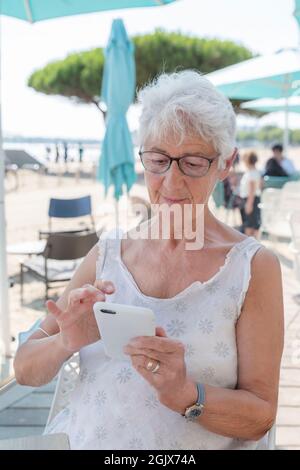 Portrait of an elderly woman writing an SMS on her mobile phone Stock Photo