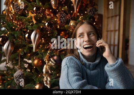 Young happy european woman holding mobile call congratulating with Christmas. Stock Photo
