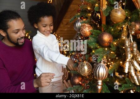 Happy biracial father and son decorate Christmas tree Stock Photo