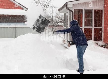man in winter clothes shoveling snow during snowstorm Stock Photo