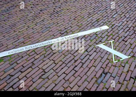 Pavement with x-axis of the Netherlands national triangle system. Dutch text: zero point national triangular measurement cadastre. Building Onze Lieve Stock Photo
