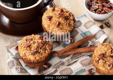 Cinnamon streusel nut muffins and cup of coffee on a wooden table Stock Photo