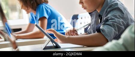 Concentrated Asian schoolboy using tapping tablet. Close up. Cut. Stock Photo