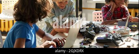 Multiethnic schoolkids building robots at STEM engineering educational class. Stock Photo