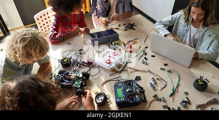 Group of multiracial schoolkids at stem class building robot. Table top view. Stock Photo