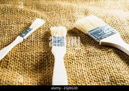 A closeup shot of three unused brushes on a burlap background Stock Photo