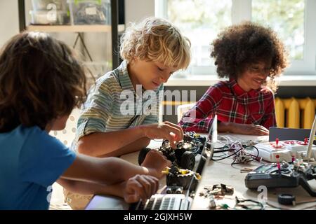 Diverse schoolkids building robotic technologies at STEM educational class. Stock Photo