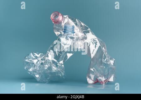 Composition of two used crushed plastic bottles on the blue background. Recycling concept. Stock Photo