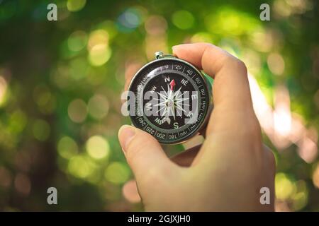 Traveler holding the compass in hand, forest background Stock Photo