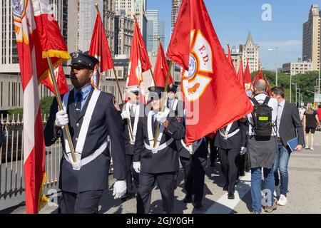Members of the FDNY Battalion 57in Brooklyn lead a precession ovver the Brooklyn Bridge to the Co-Cathedral of St. Joseph. The marchers will carry 25 flags, with 24 FDNY flags representing the 23 members of Battalion 57 who were lost at the World Trade Center and a brother of a member of Battalion 57 who also died that day and one American flag. New York City, NY USA September 11, 2021 (Photo by Steve Sanchez/Sipa USA). Stock Photo