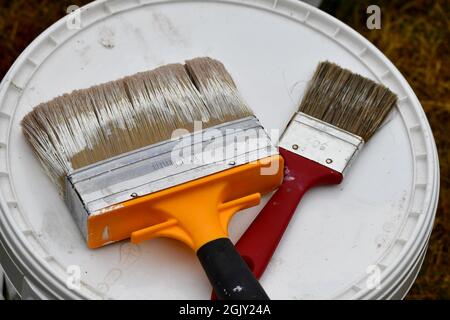 Closeup of paint brushes lying on top of paint bucket Stock Photo