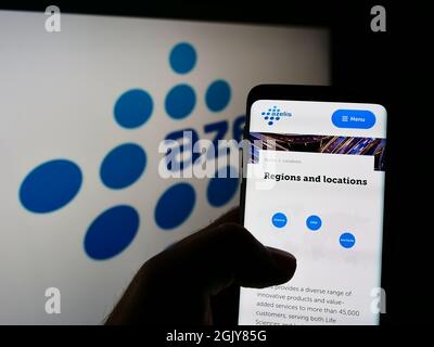 Person holding cellphone with web page of Belgian chemical company Azelis Holding SA on screen in front of logo. Focus on center of phone display. Stock Photo