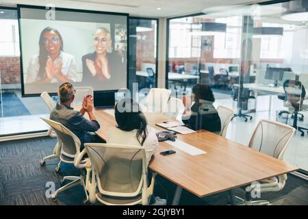 Creative businesspeople clapping during a video conference. Group of modern businesspeople attending a virtual meeting with their partners in a boardr Stock Photo