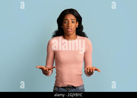 I Don't Know. Unsure Young Black Female Shrugging Shoulders And Spreading Arms Stock Photo